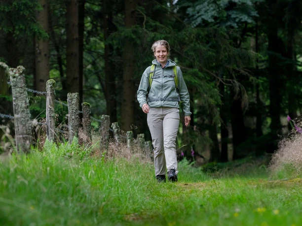 Kerstin Rubel Kerstin Rubel wandert lächelnd mit Rucksack auf einem grünen Waldweg in Wipperfürth.
