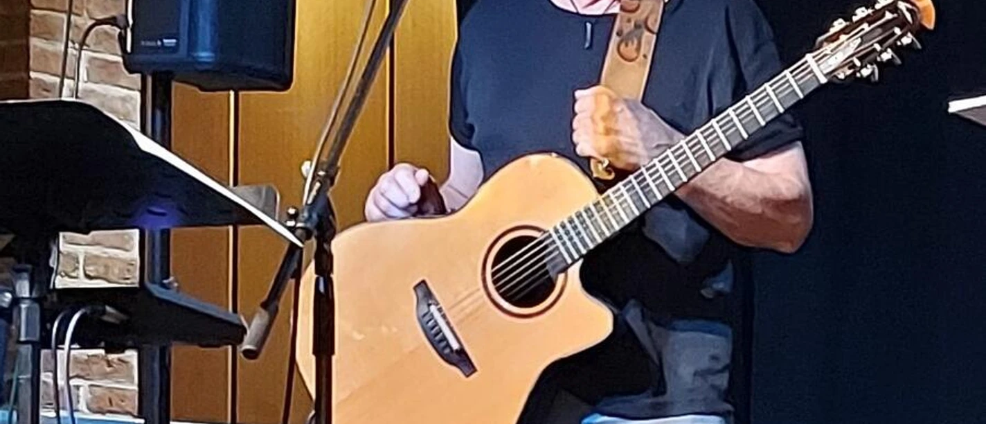 Espelkamper Rudelsingen - Gerd Langwald Musiker mit Akustikgitarre auf Bühne beim Espelkamper Rudelsingen im Kino