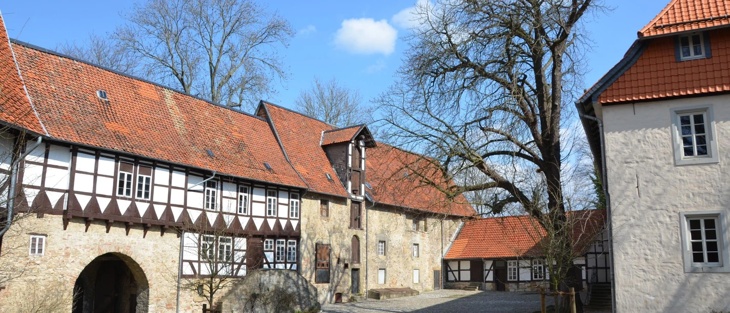 Blick in den Innenhof der Wasserburg Gebhardshagen mit Fachwerkfassade, Steinmauern und Torbogen.