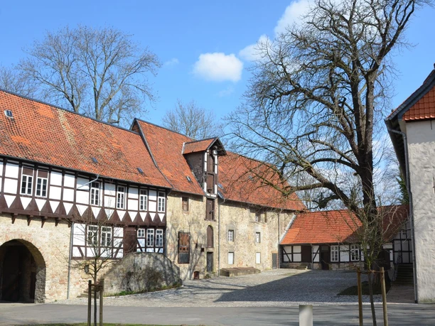 Blick in den Innenhof der Wasserburg Gebhardshagen mit Fachwerkfassade, Steinmauern und Torbogen.