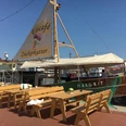 c38f6a34-613c-4426-91ca-35c6af237cf2_WEB.jpg Eiscafé Zuckerkutter im Neuen Hafen mit Tischen und Bänken auf der Kaje davor