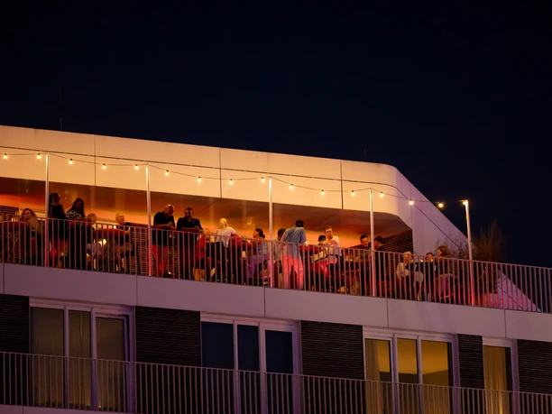 CAL_0718 (c) Carmen Lindemann_Erlebnis Bremerhaven_CC0_WEB.jpg Abendlicher Blick hoch zur Dachterrasse der New York Bar, auf der Menschen Cocktails und Drinks genießen