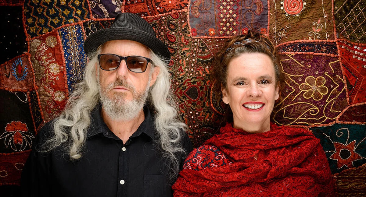 Nessi Tausendschön Kabarettistin Nessi Tausendschön mit Begleiter vor farbigem Stoffhintergrund