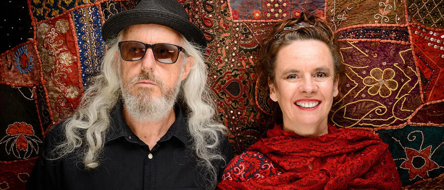 Nessi Tausendschön Kabarettistin Nessi Tausendschön mit Begleiter vor farbigem Stoffhintergrund