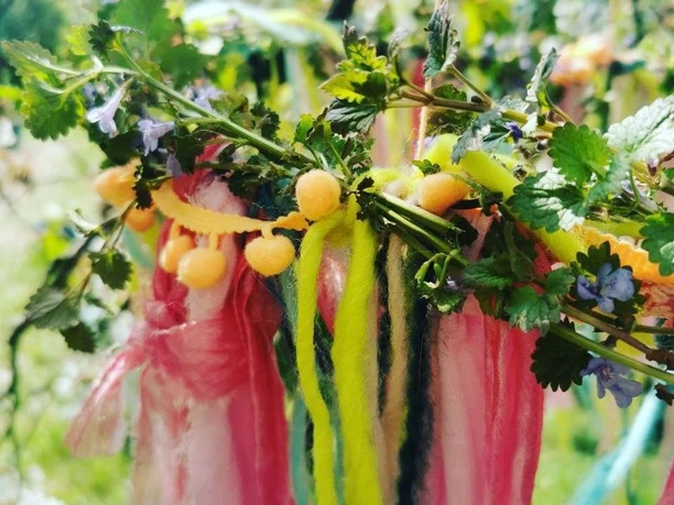 Oh du schöne Maienzeit Ein geflochtener Kranz aus Wildkräutern mit kleinen Beeren und bunten Stoffbändern.