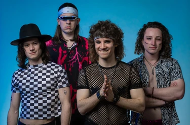 Chicago Lane Band Chicago Lane in 80er-Jahre-Outfits vor blauem Hintergrund.