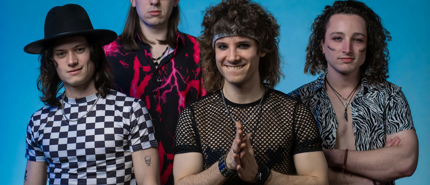 Chicago Lane Band Chicago Lane in 80er-Jahre-Outfits vor blauem Hintergrund.