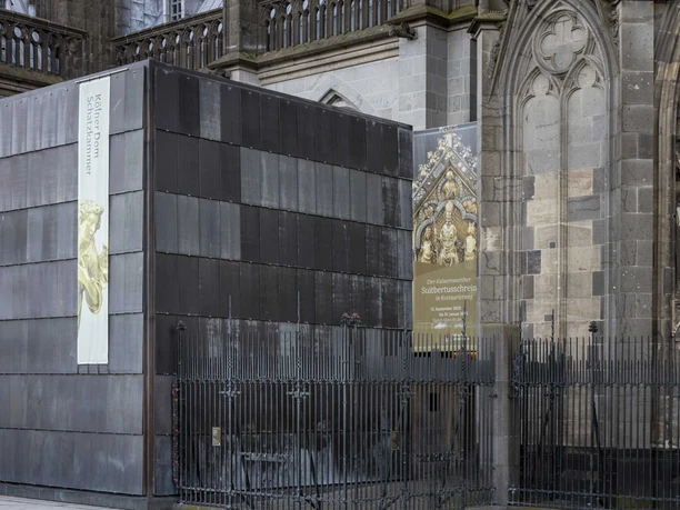 Domschatzkammer Moderner dunkler Baukörper vor der reich verzierten gotischen Fassade des Kölner Doms.
