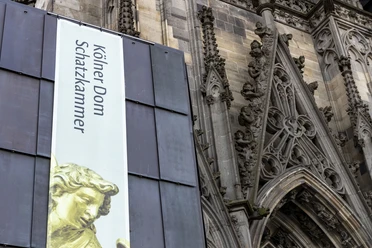 Domschatzkammer Banner zur Kölner Domschatzkammer vor der reich verzierten gotischen Außenfassade