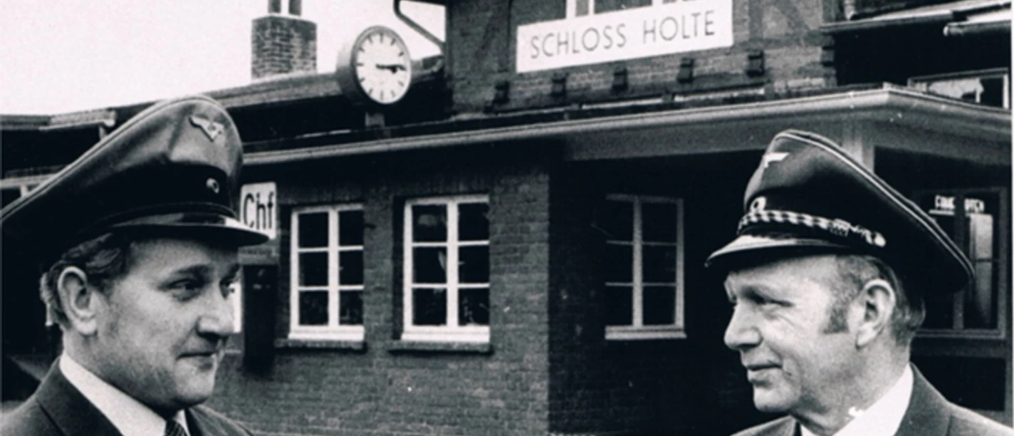 Bild11.png Historisches Foto vom Bahnhof Schloß Holte mit zwei Bahnbeamten vor dem Gebäude