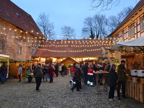 Weihnachtsmarkt_Wasserburg-Gebhardshagen_HD_16zu9.JPG Besucher auf dem Adventsmarkt im beleuchteten Innenhof der historischen Wasserburg Gebhardshagen.