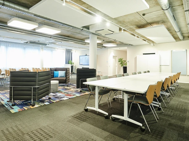 Auditorium - Multifunktionaler Büroraum Multifunktionaler Büroraum mit Besprechungstischen, Lounge-Bereich und Sitzreihen für Präsentationen in einem modernen, hellen Ambiente.