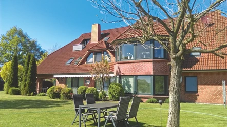 Pension Heuer.jpg Rotes Backsteinhaus der Pension Heuer in Brietlingen mit gepflegtem Garten und Sitzgruppe im Freien.
