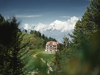 Historische Architektur am Berg Die markante Villa Cassel thront auf einem grünen Bergrücken, ein beliebtes Ziel beim Wandern Aletsch Arena.