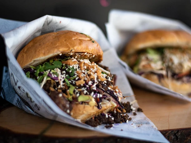 Gourmet Festival am Schokoladenmuseum in Köln Zwei belegte Gourmet-Burger mit Sesam, Kräutern und Gemüse in Papier auf Holzbrett