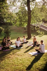 Group of women practice meditate in city park on summer sunny morning Group of women practice meditate in city park on summer sunny morning