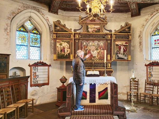 Gästeführer zeigt auf das Altarbild in der Oeser Kirche