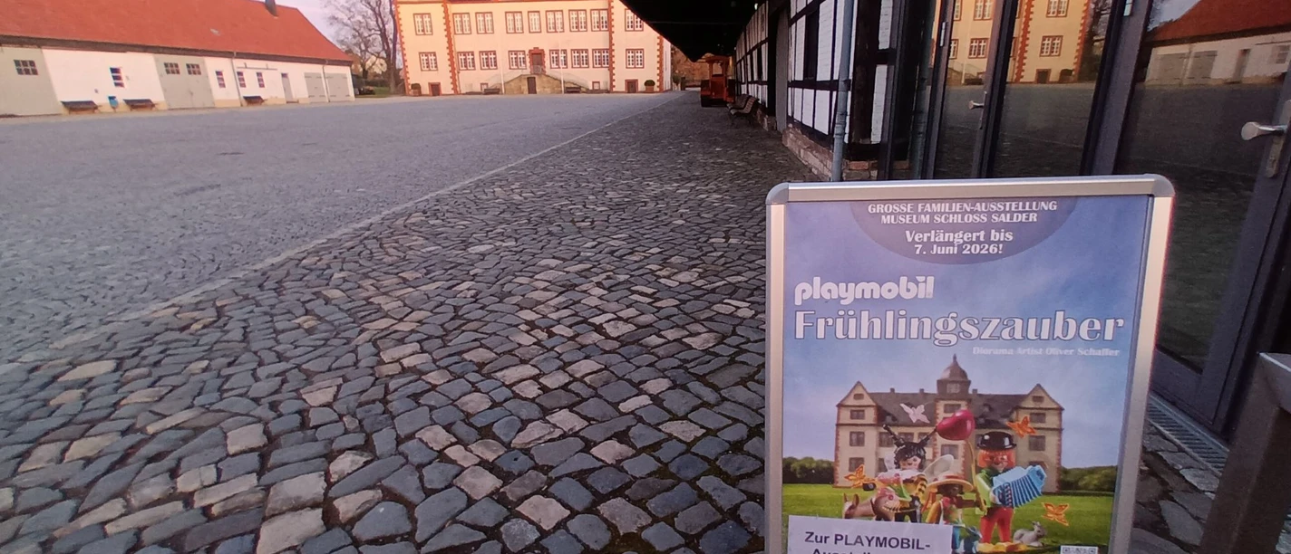 Aufsteller Fruehlingszauber Playmobilausstellung Schloss Salder_HD_16zu9.jpg Plakatständer für Playmobil-Ausstellung Frühlingszauber vor Schloss Salder mit Wegweiser.