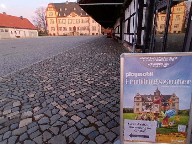 Aufsteller Fruehlingszauber Playmobilausstellung Schloss Salder_HD_16zu9.jpg Plakatständer für Playmobil-Ausstellung Frühlingszauber vor Schloss Salder mit Wegweiser.