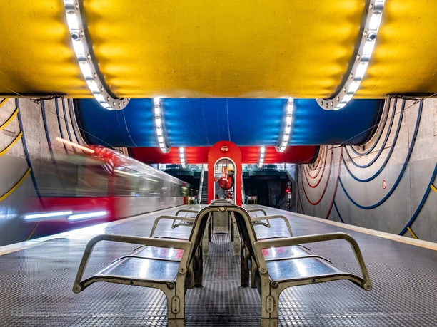 Rochusplatz stop Subway station with colorful ceiling arches, rows of seats and passing trains