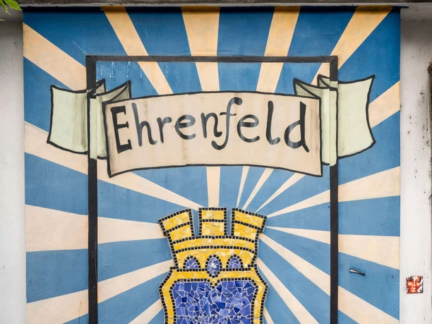 Ehrenfeld Mural with Ehrenfeld lettering and yellow-blue mosaic coat of arms against a radial background