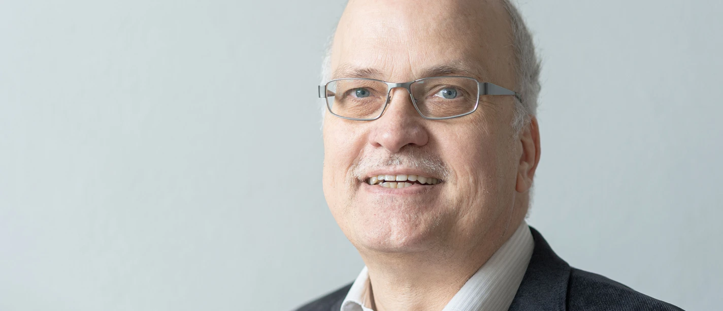 Bauerkaemper Arnd Porträt eines älteren Mannes mit Brille, Sakko und hellem Hemd vor grauem Hintergrund