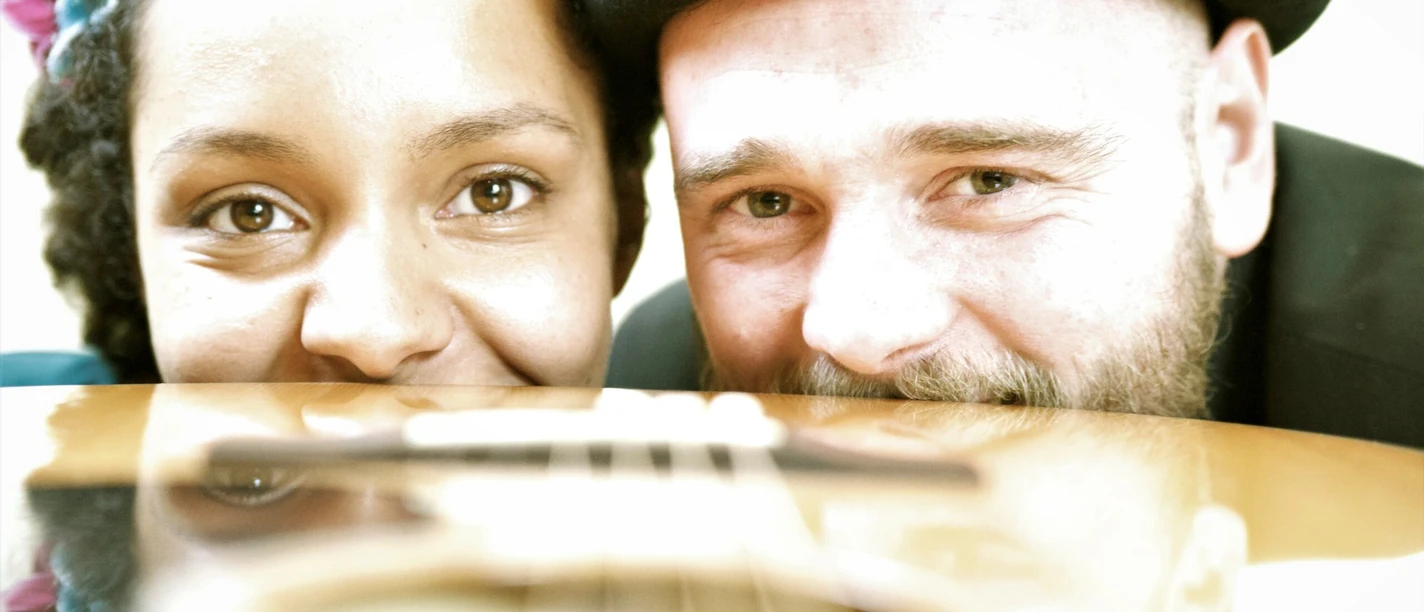 White Coffee Zwei Musiker lächeln hinter einer Gitarre in Nahaufnahme beim Konzert.