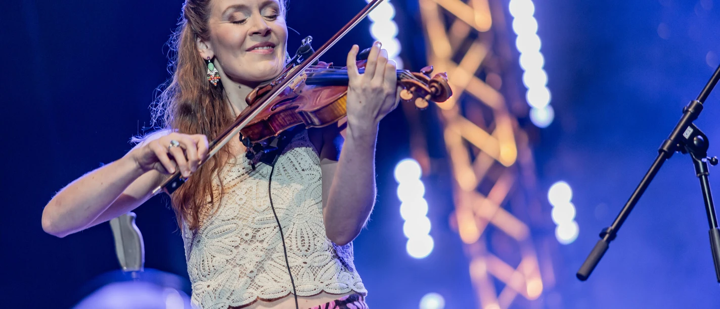 Joerdis Tielsch Pressefoto Geigerin spielt mit geschlossenen Augen auf Bühne vor blauem Licht