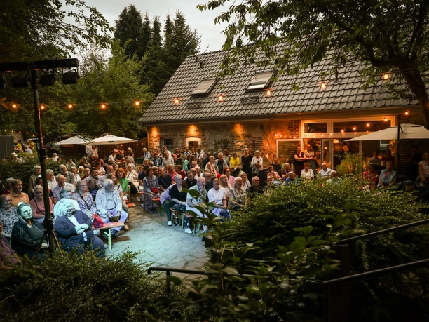 Abend-Event im Café Op dem Kamp in Erkrath Besucher:innen versammeln sich zum Abend-Event im Außenbereich des Café Op dem Kamp in Erkrath.