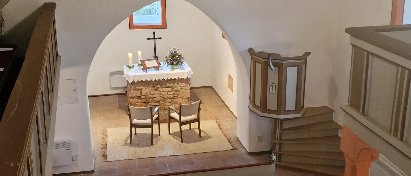 Sie sehen den Innenraum mit Blick von einer Treppe in das Kirchenschiff direkt auf den Altar.