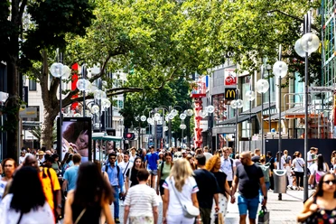 Schildergasse Busy shopping street with lots of passers-by, stores and shade from large trees