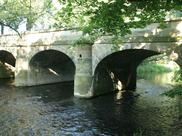 Franzosenbruecke_Hohenrode_HD_16zu9.jpg Historische Steinbogenbrücke über einen Fluss, eingerahmt von grünen Bäumen in Salzgitter-Hohenrode.
