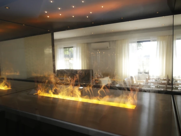 Kaminfeuer Waldklause (c) Camren Stickling.JPG Modernes Kaminfeuer im Gastraum der Waldklause mit Blick auf Sitzbereich und Fensterfront