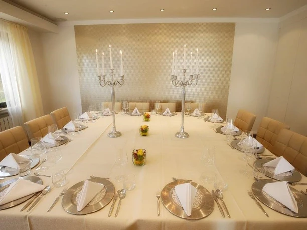 Festlich gedeckte lange Tafel mit weißen Servietten und silbernen Kerzenleuchtern