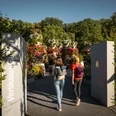 O-Schatz-Park-Freizeitpark-Region-Leipzig-Garten-Eingang-Ausflug-Philipp-Herfort-Photography-leipzig-travel.jpg Eingang zum O-Schatz-Park, zwei Frauen gehen hinein, im Hintergrund blühen bunte Blumen und verschiedene Pflanzen.