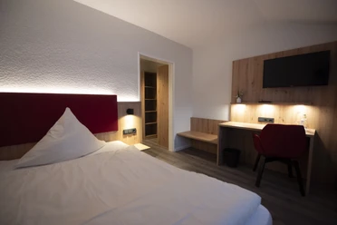 Zimmer in der Waldklause Modernes Hotelzimmer mit Doppelbett, Schreibtisch, TV und Holzdetails