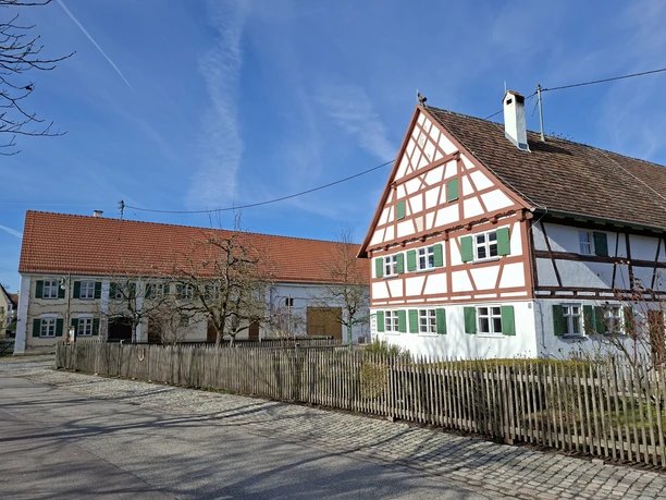 Kreisheimatstube Stoffenried Zwei traditionelle Bauernhäuser mit Fachwerk und Zaun unter klarem blauem Himmel.