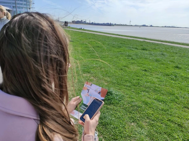 135849 (c) Tanja Albert_Erlebnis Bremerhaven_WEB.jpg Frau mit Smartphone auf dem Weserdeich in Bremerhaven auf Geocaching Tour