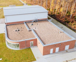 Gebäude.jpg Backsteinbau des Wasserwerks mit Flachdach, Technikaufbauten und Wald am Rand