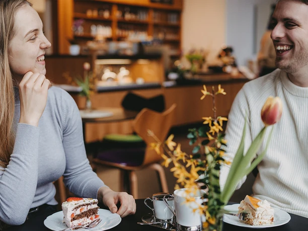 Museumscafé LUNA_ Kaffee & Kuchen ©Sophie Wolter.jpg Lachendes Paar genießt frischen Kuchen und Kaffee an einem Tisch im Museumscafé Luna im Museum Lüneburg.