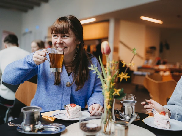 Tee & Torte – ein wahrer Genuss im Museumscafé LUNA Eine Frau trinkt im Museumscaßé eine Tasse Tee, vor ihr steht ein Stück Torte auf dem Tisch.