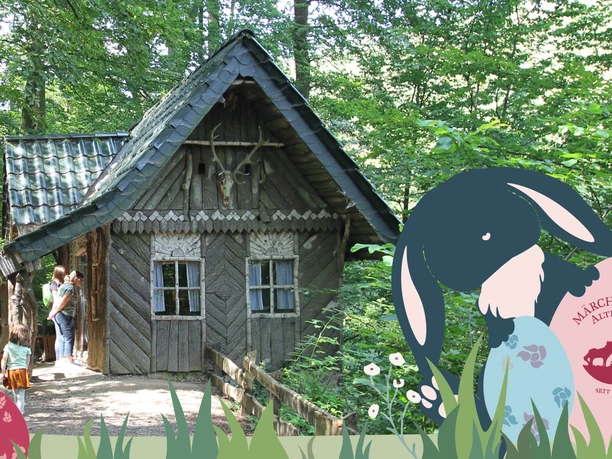 Osterzeit im Märchenwald Osterhase und bunte Eier vor einem Holzhaus im Märchenwald Altenberg mit Besucher:innen auf einem Weg.