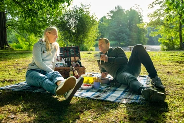 Eine Reise für die Sinne Paar beim Picknick auf Decke im Grünen am See im Stadtpark Gütersloh