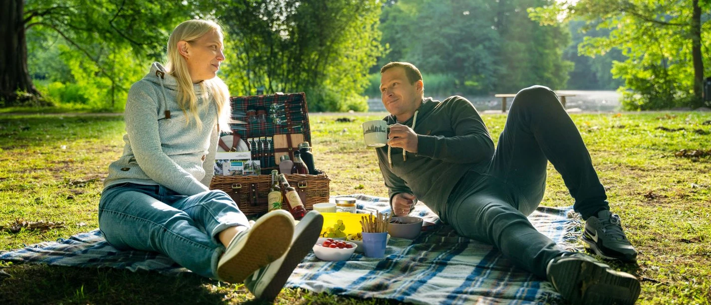 Eine Reise für die Sinne Paar beim Picknick auf Decke im Grünen am See im Stadtpark Gütersloh