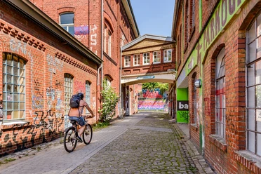 Weberei Gütersloh Radfahrer in Backsteingasse der Weberei Gütersloh mit Graffiti an den Wänden