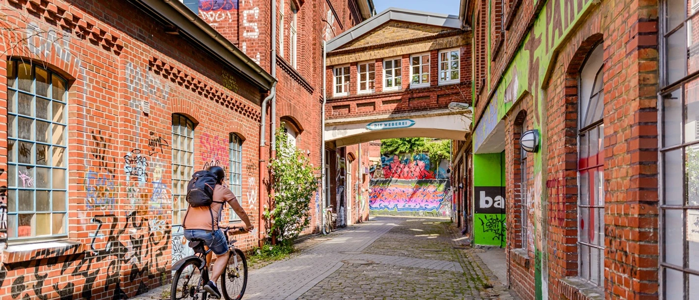 Weberei Gütersloh Radfahrer in Backsteingasse der Weberei Gütersloh mit Graffiti an den Wänden