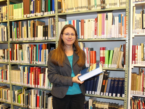 IMG_0419 (c) Dörte Behrmann_Erlebnis Bremerhaven_WEB.jpg Eine Frau hält im Stadtarchiv Bremerhaven ein dickes Buch in den Händen