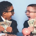 alter-verwalter.jpg zwei kleine Kinder im Anzug mit Dollarnoten und einem Sparschwein auf dem Tisch in der Hand lächelt sich an