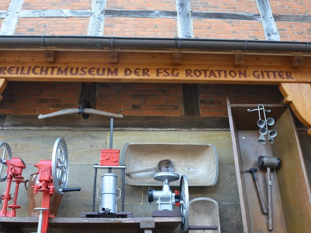Freilichtmuseum_Gitter (8)_HD_16zu9.JPG Historische Werkzeuge und Maschinen unter dem Holzschild Freilichtmuseum Gitter.