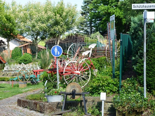 Freilichtmuseum_Gitter (3)_HD_16zu9.JPG Historische landwirtschaftliche Geräte stehen draußen im Freilichtmuseum Gitter neben einem Weg.